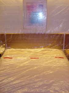 Hotel room bed (and headboard and side tables) covered in clear plastic